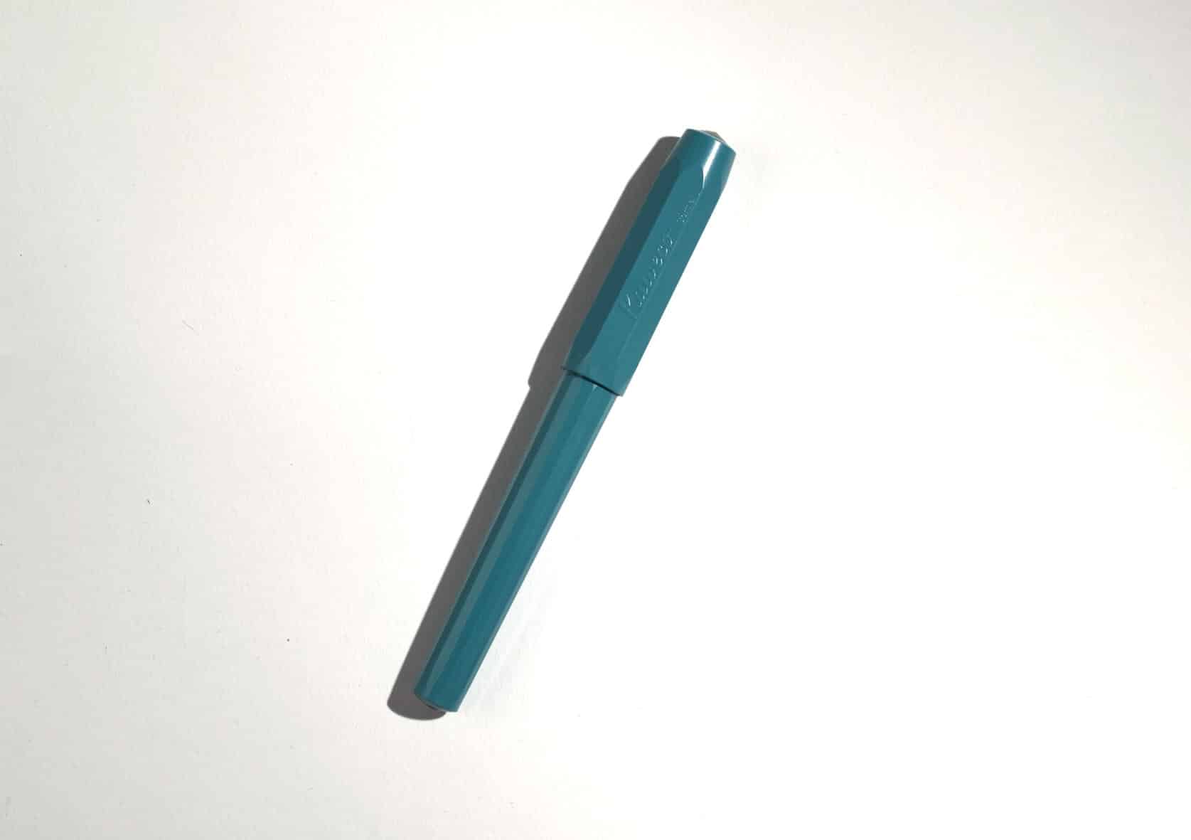 A teal-coloured plastic fountain pen on white surface.