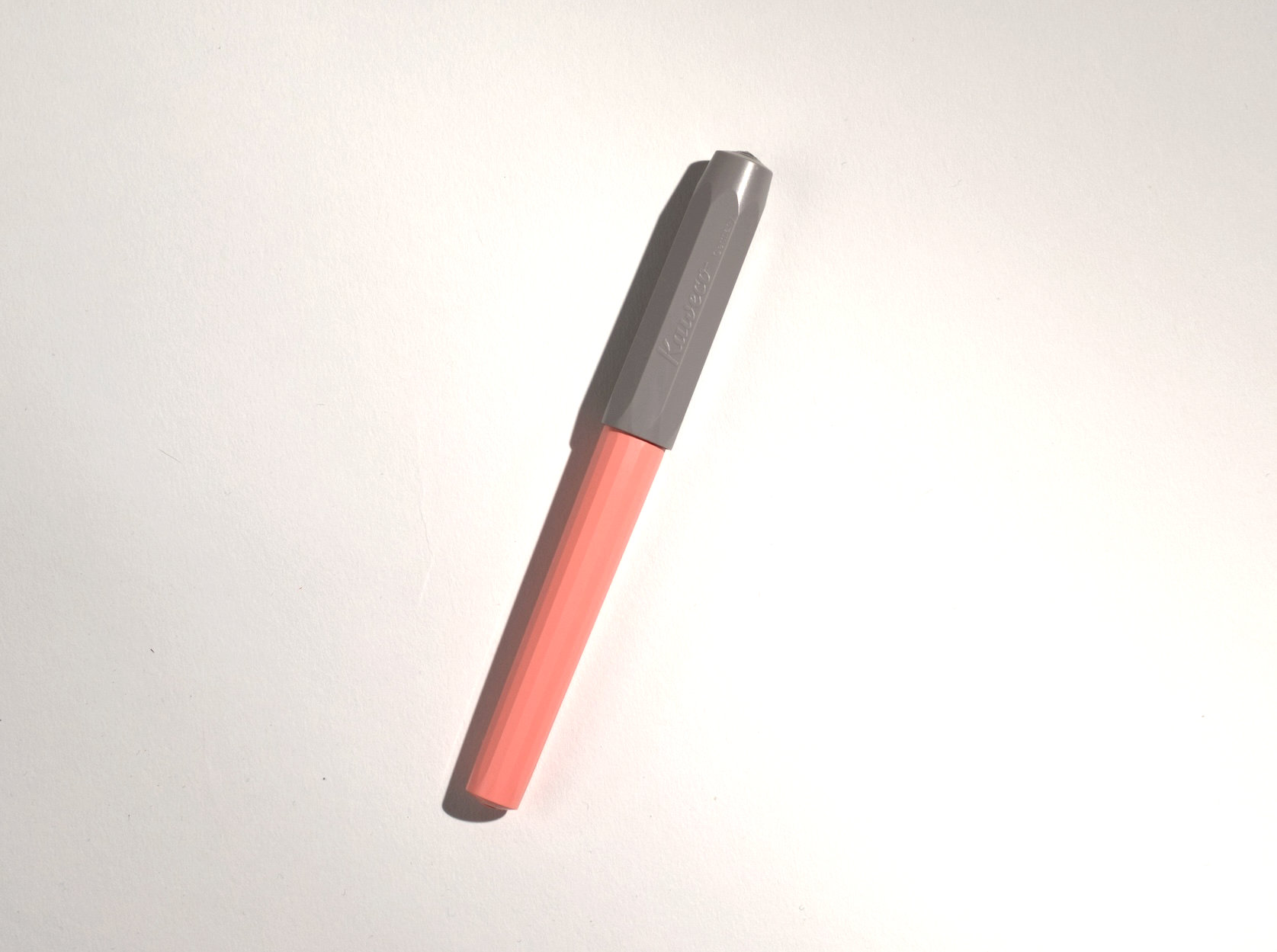 A two-toned pink-grey-coloured plastic fountain pen on white surface.