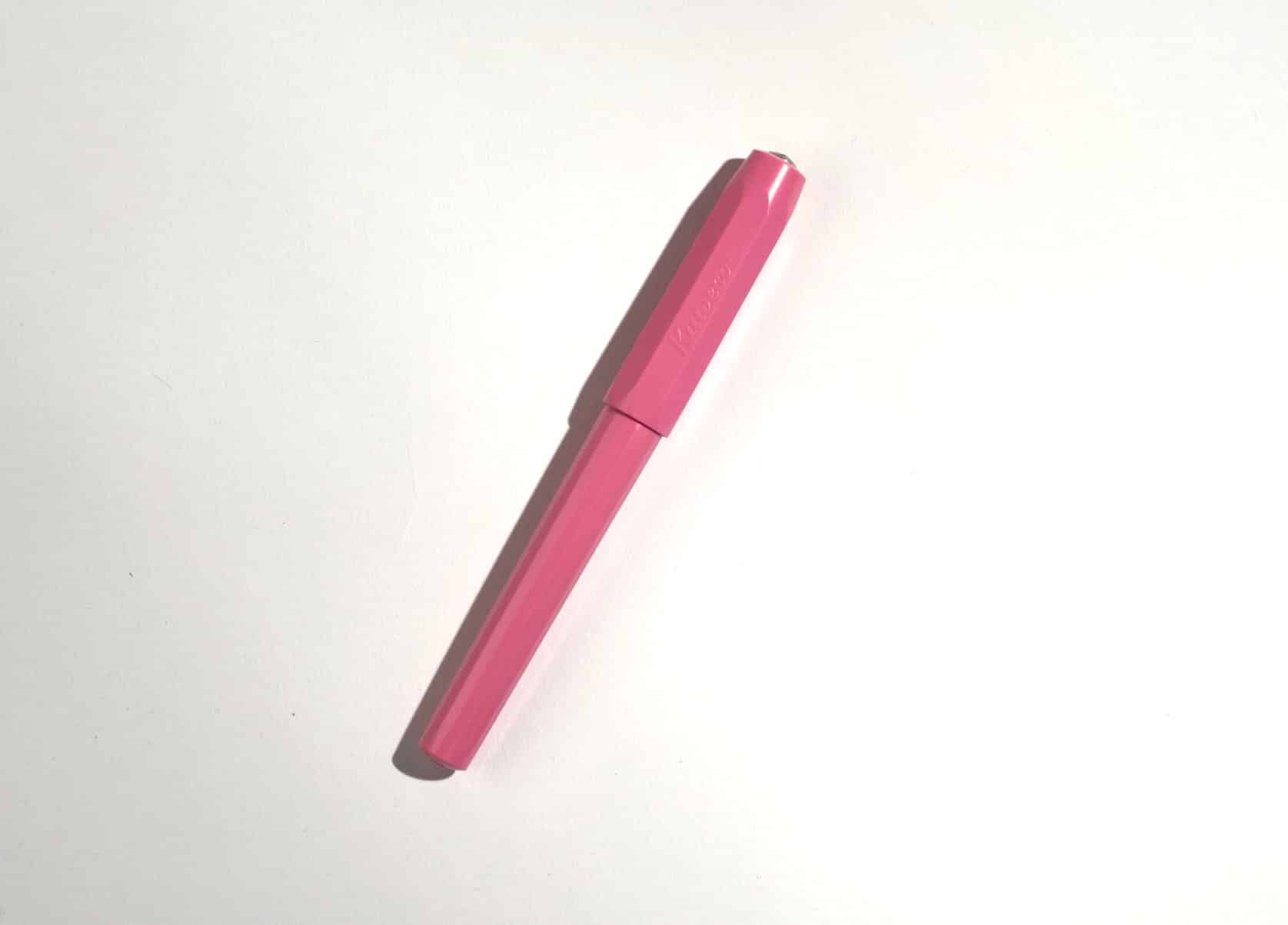 A pink plastic fountain pen on white surface.