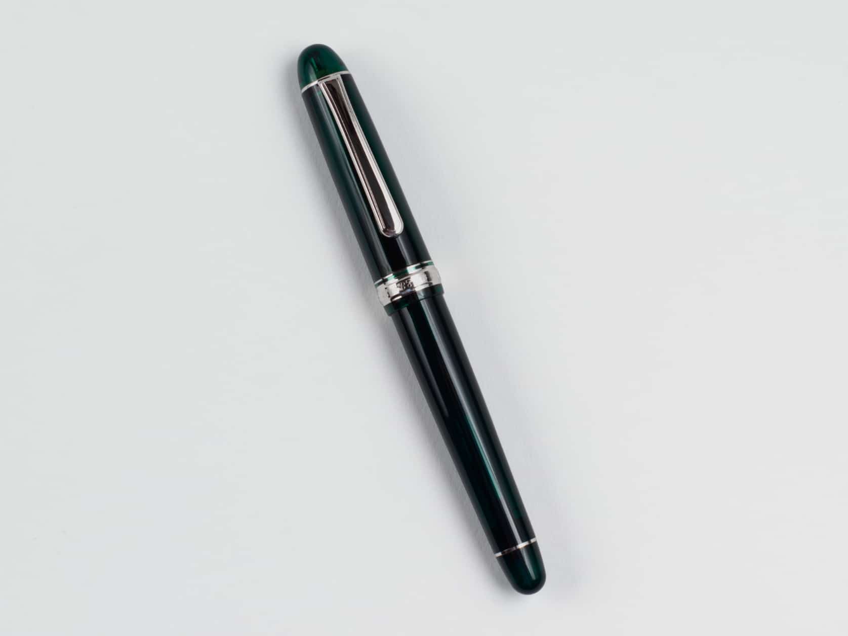 Translucent green fountain pen with a silver clip. Silver ring with embossed pen name at the base of the cap