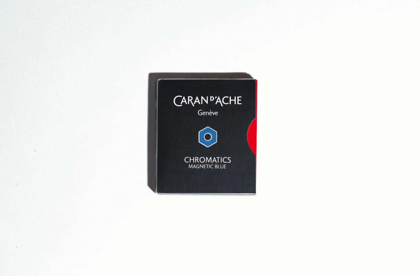 Small black box with a red semi circle on the right side. On the front is the Caran d'Ache logo, a blue hexagon and text reading: Chromatics Magnetic Blue.