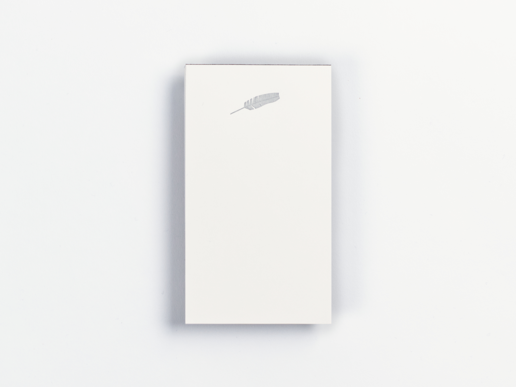 White notepad with a silver feather illustration at the top