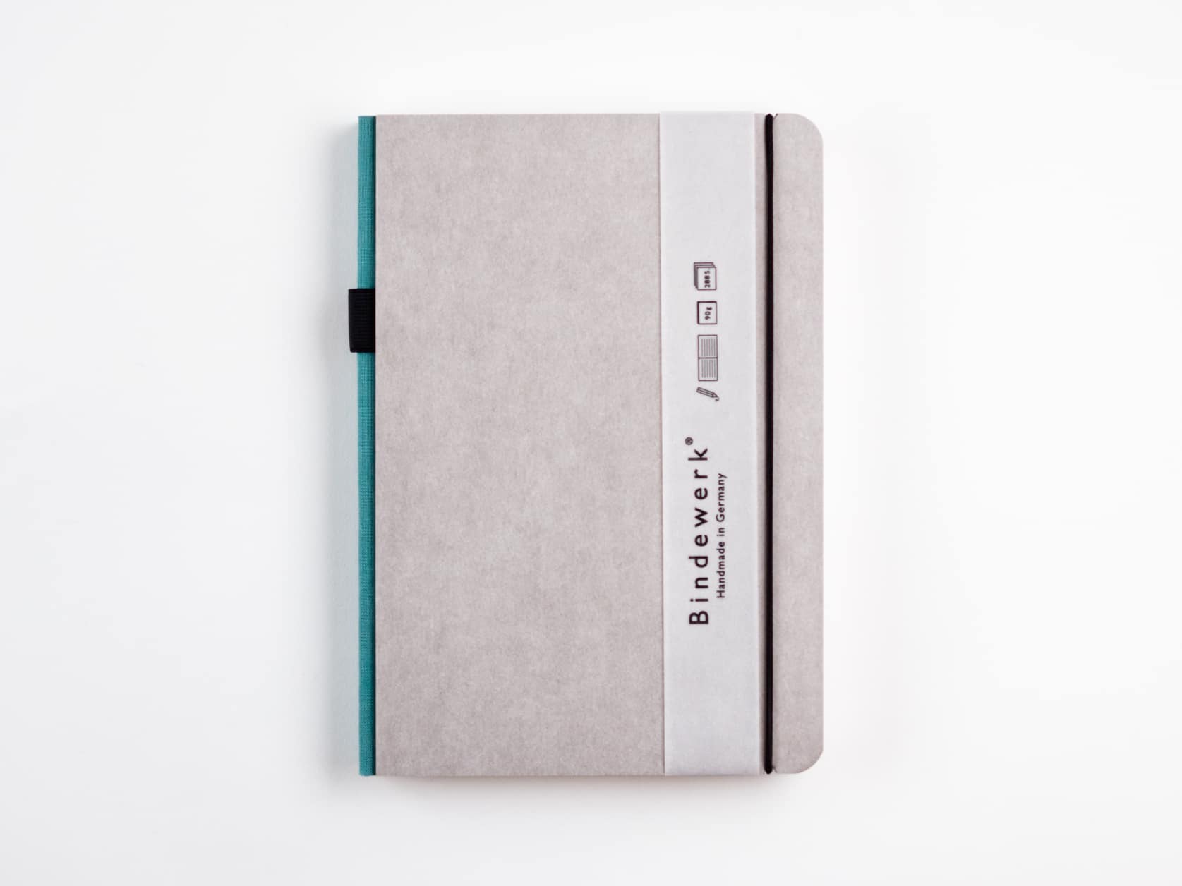 Grey notebook with a turquoise spine, a black elastic and a slim sleeve with the Bindewerk logo and the words Handmade in Germany.