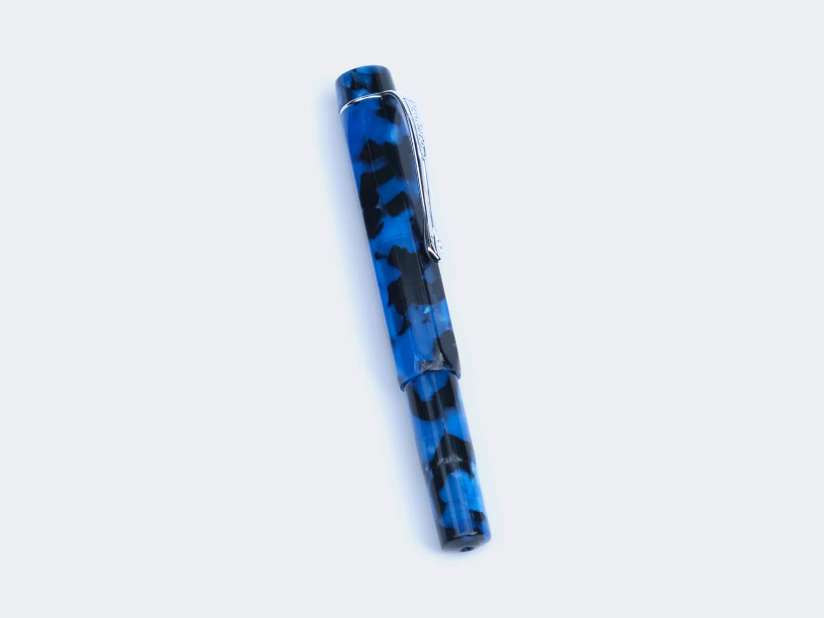 Blue fountain pen with a black marbled pattern. It has a silver clip and ring around the top