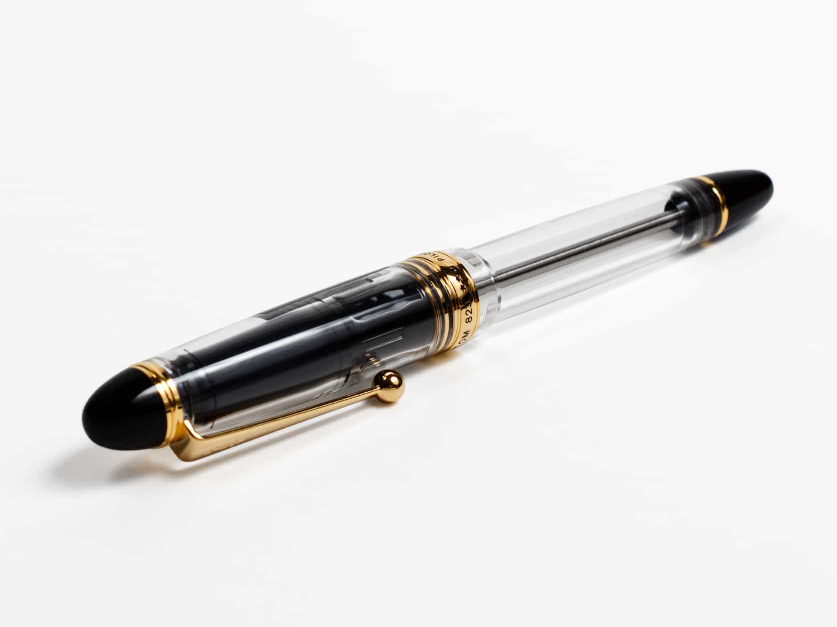 Transparent fountain pen with black ends, a golden clip and a golden ring around the bottom of the cap