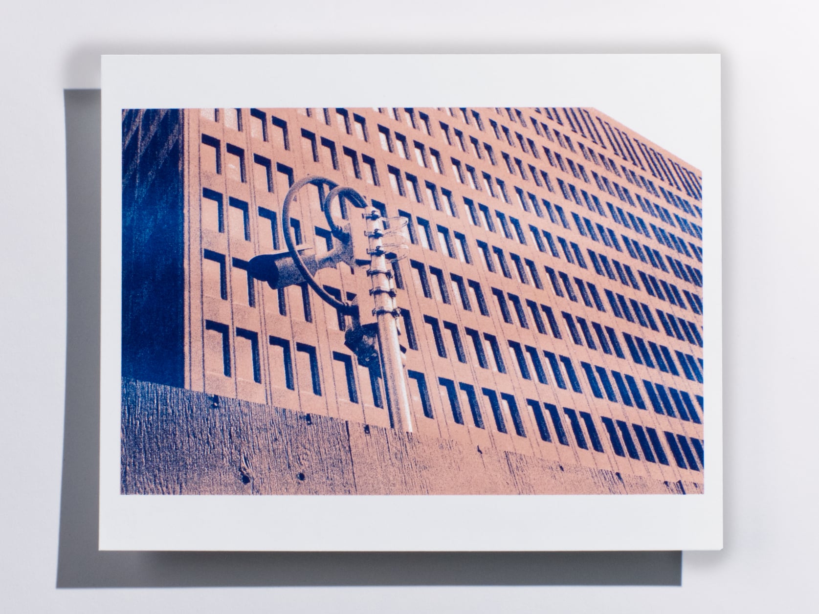 Photography print of a surveillance camera pole in front of a large building