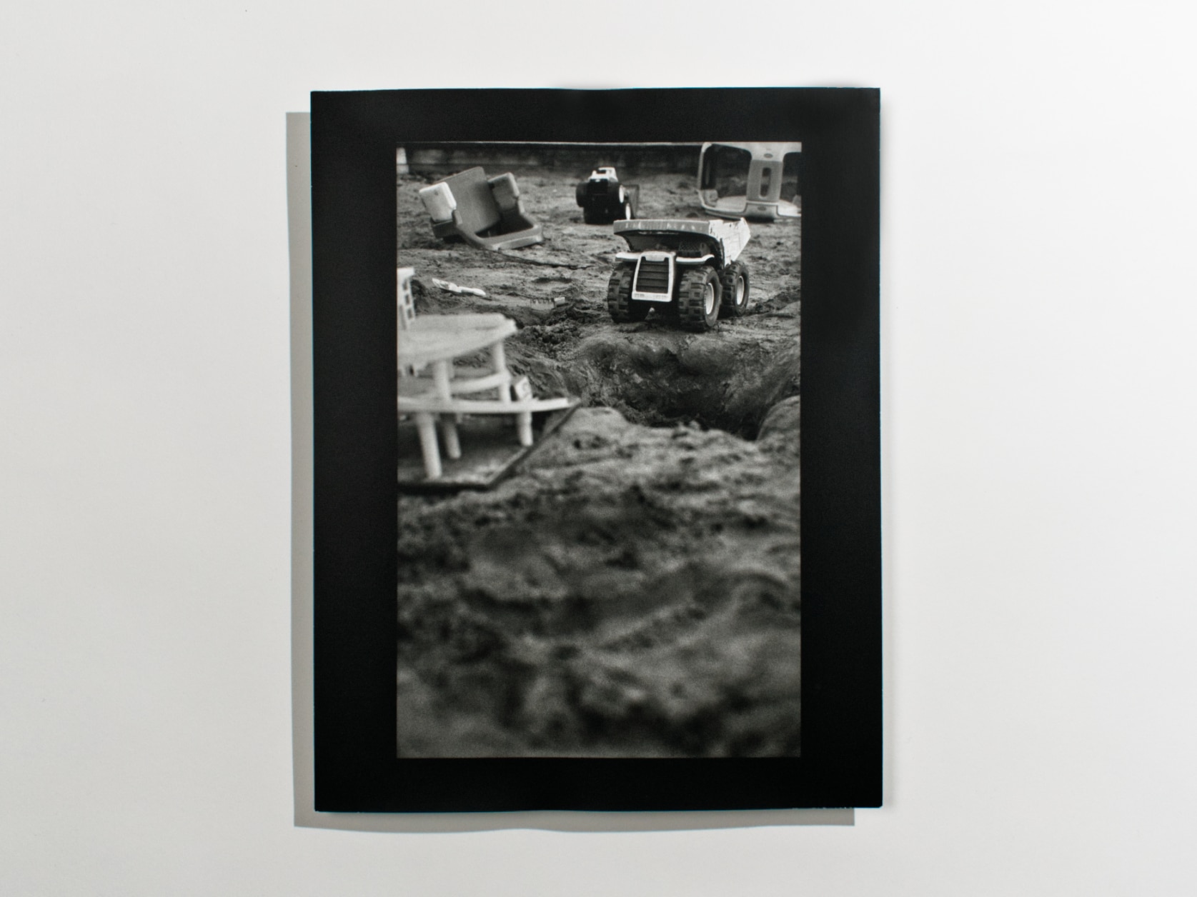 Black and white photography print of a closeup shot of toys in a sandbox