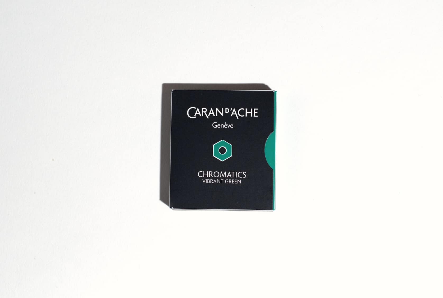 Small black box with a a green semi circle on the right side. On the front is the Caran d'Ache logo, a green hexagon and text reading Chromatics Vibrant Green.